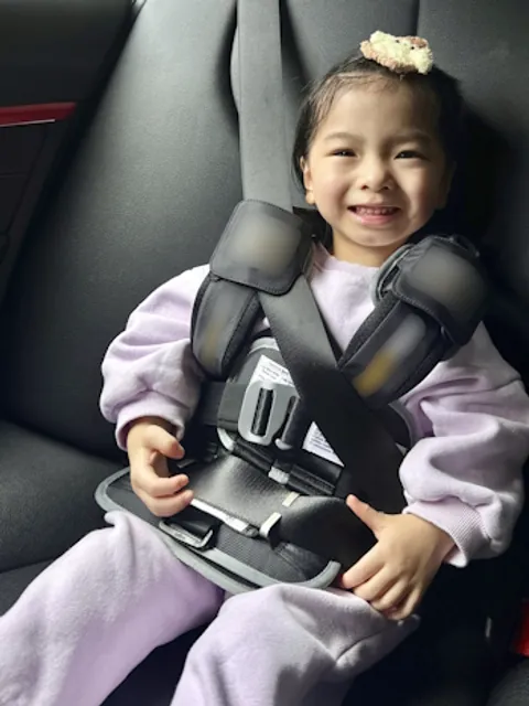 Child wearing a wearable safety restraint vest with the vehicle seat belt routed through it